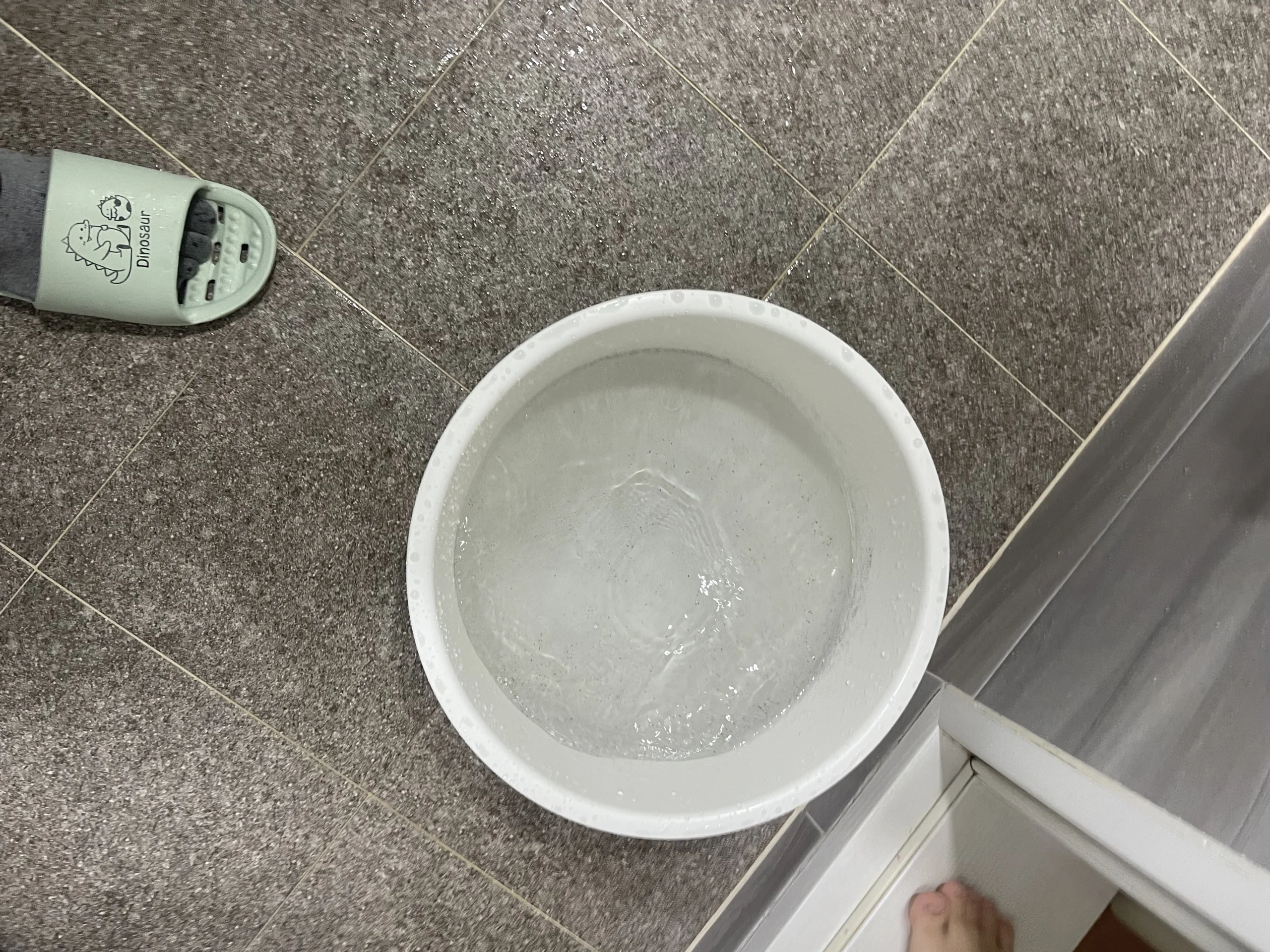 하부장 앞바닥에 물받이용 대야를 받쳐두고 안쪽에서 작업이 진행 중인 모습으로 보인다.